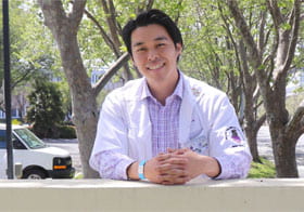 James Yu, Palmer West student, behind the Palmer West Chiropractic Clinics sign