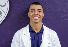 Jacob Williams in white clinic coat against purple background.