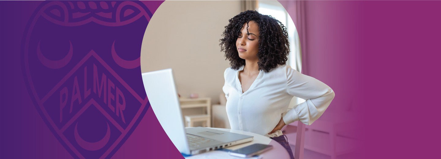 Woman holding back while working on a laptop.