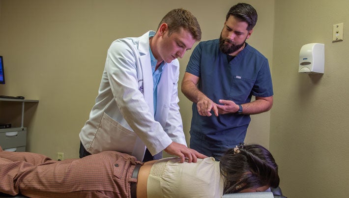 Student and instructor adjusting a client's back.