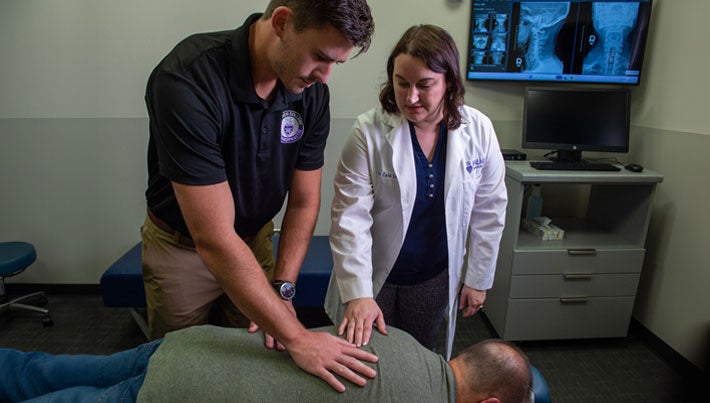 Instructor helping intern survey a client's back.