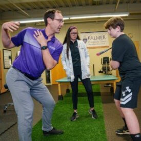 Dr. Buns and intern working with client on golf swing.