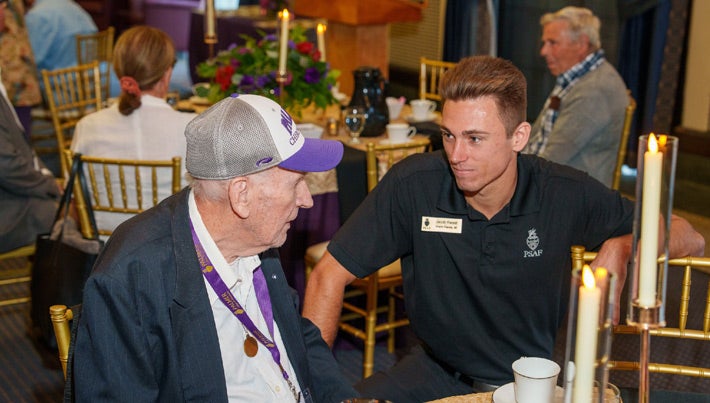 Alumni and student talking at a Homecoming banquet.