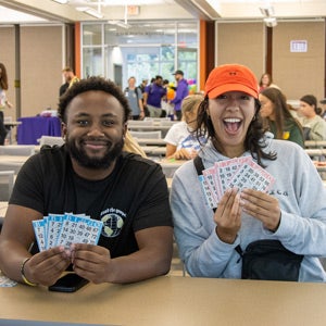 Two students posing with Bingo cards. 