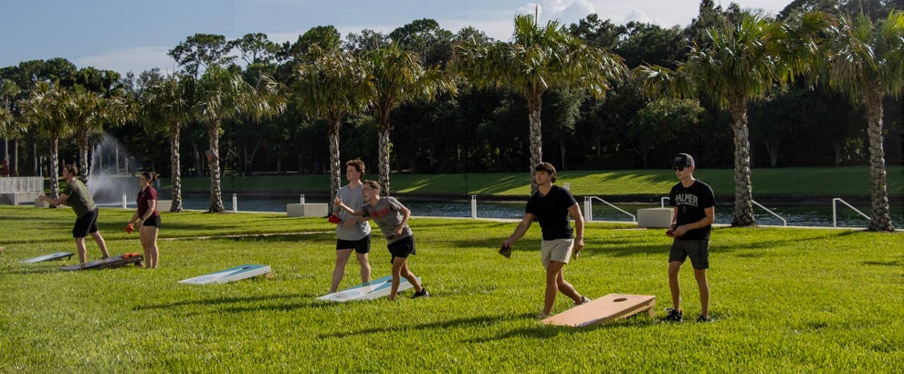 Students playing cornhole on the yard of Florida Campus.